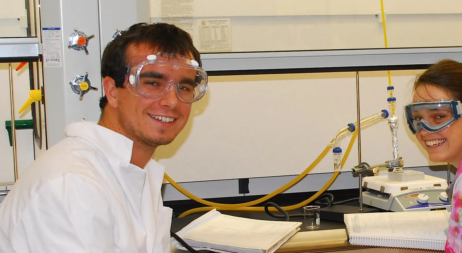 two students with goggles in chemistry lab smiling