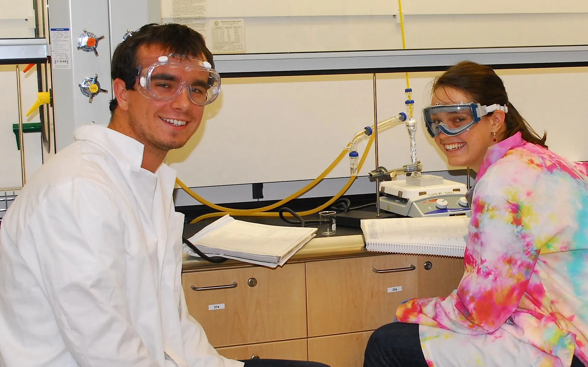 two students with goggles in chemistry lab smiling