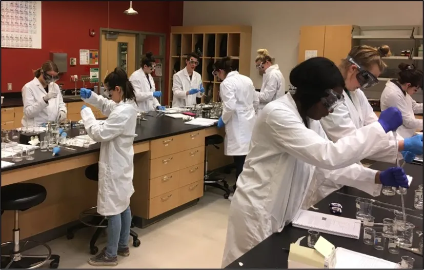 students in lab coats and goggles in chem lab